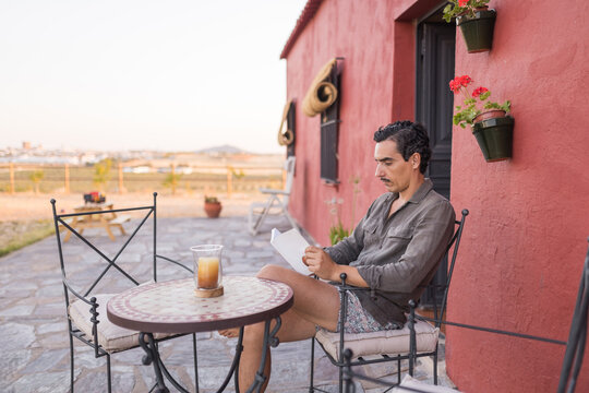 Man reading on patio at country house during summer vacation