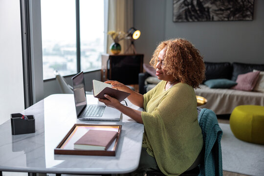 Professional woman reading notes while working at home desk