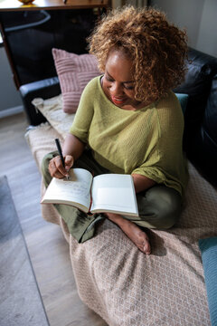 A woman writes in her journal on a couch