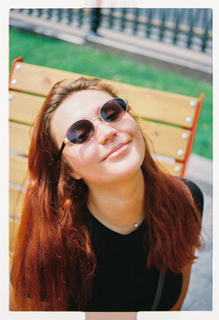 A young woman tilts her face to the sun on a park bench