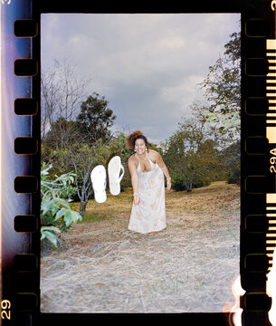 Woman tossing sandals playfully on a hillside path