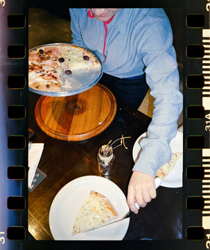 Person serving pizza slices at a restaurant table
