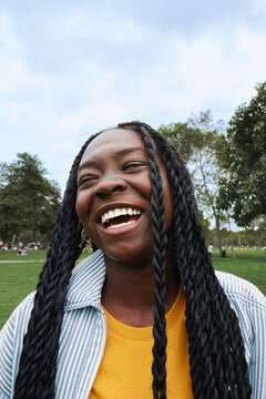 Happy young woman laughing outdoors in park