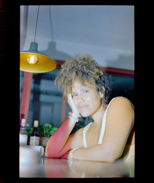 Woman resting chin on hand under pendant lamp