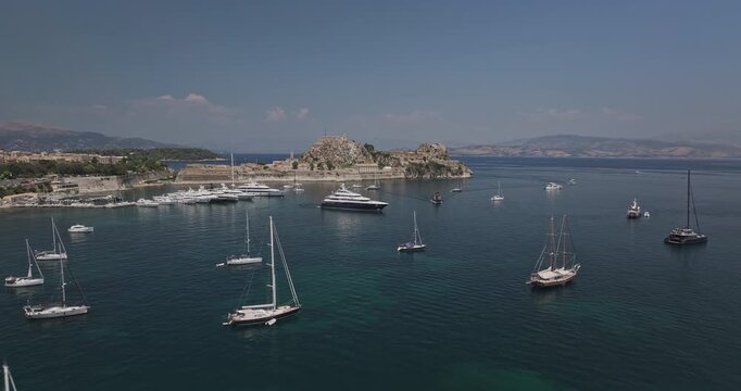 Corfu Greece Aerial v1 low flyover around Garitsa Bay, capturing yachts and sailboats in the marina, with views of the fortress and town center - Shot with 5k Camera - July 16th 2024