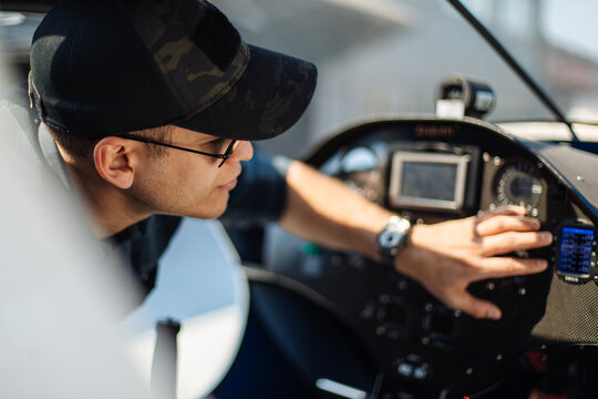 Young Pilot Adjusting Controls Inside Small Plane Cockpit