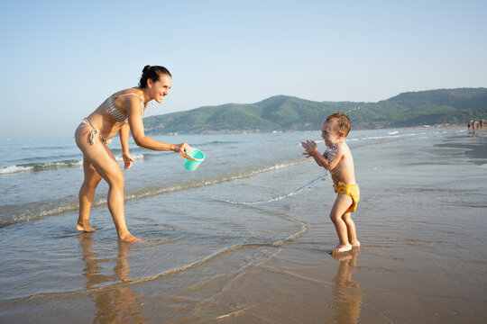 Mother and toddler playing with water on beach