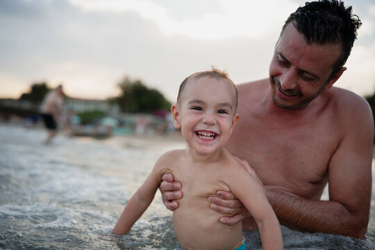 Father supporting son playing in the ocean