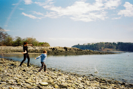 Two brothers skip rocks together on the coast of Maine