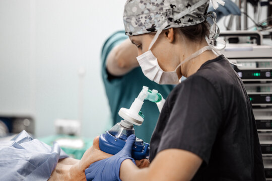 Anesthesiologist supports patient breathing with an oxygen mask and anesthesia equipment during surgery.