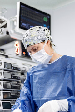 Female healthcare professional focused on patient care during anesthesia and surgery in hospital.