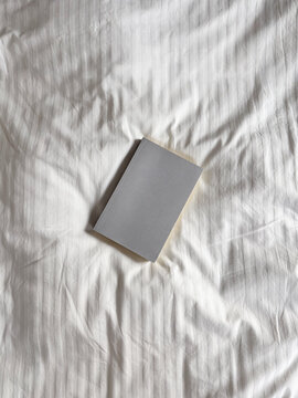 Overhead Flat Lay of Book on White Bedding