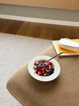 Healthy Berry Oatmeal Bowl on Mustard Yellow Armchair with Books