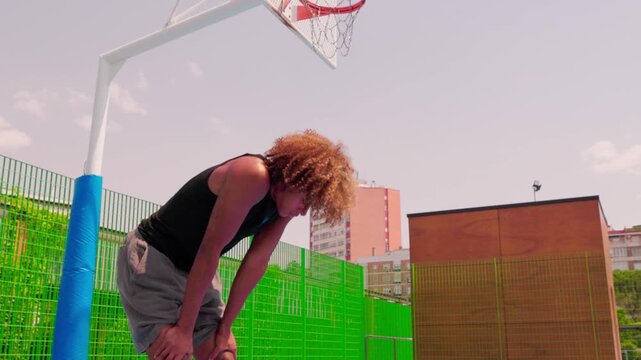 Tired athlete catching his breath on an outdoor basketball court