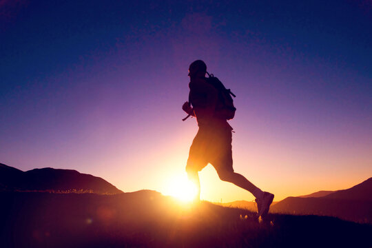 Silhouette of runner at sunrise on mountain trail