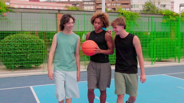 Multicultural friends walking and talking on an outdoor basketball court