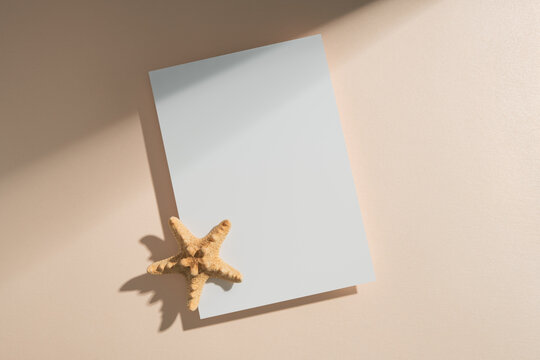 Blank card mockup with starfish on beige background with tropical shadows