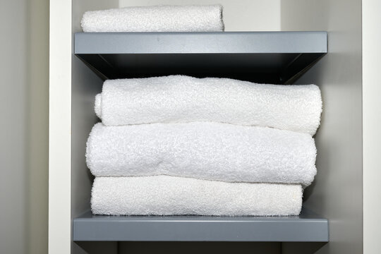 Folded white towels in the closet of a low cost hotel.
