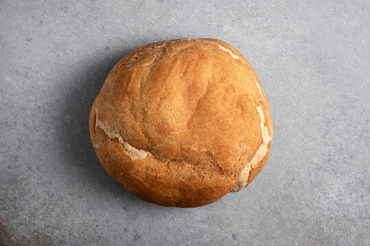 Round loaf of artisanal sourdough bread on grey background