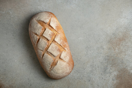 Loaf of artisanal sourdough bread on grey textured background