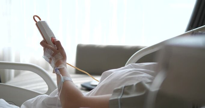 Side view of patient holding nurse call button on hospital bed