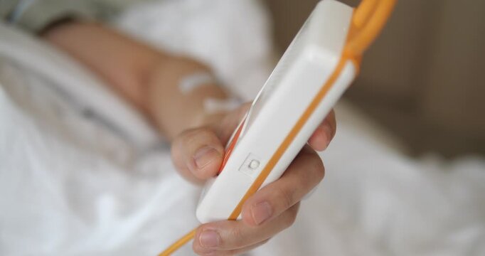 Close up of patient hand holding nurse call remote control in hospital
