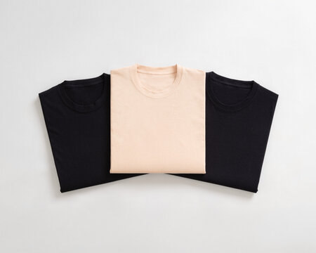 Top view flat lay of folded black and cream colored cotton t shirts arranged neatly on a white background