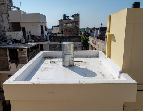 stainless steel water tank on a flat rooftop treated with white heat-resistant, sun-reflective protective coating