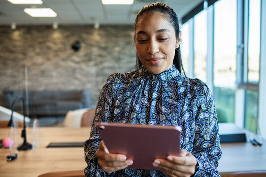 Smiling woman using a tablet in a modern office