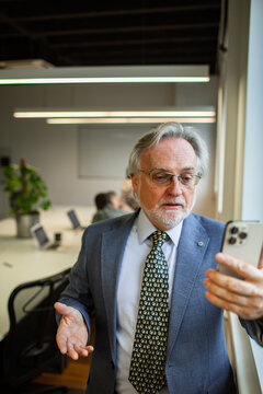 Senior executive on smartphone video call in conference room