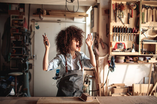 Woman singing with earbuds in woodworking shop