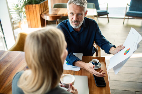 Man presenting chart to woman in cafe