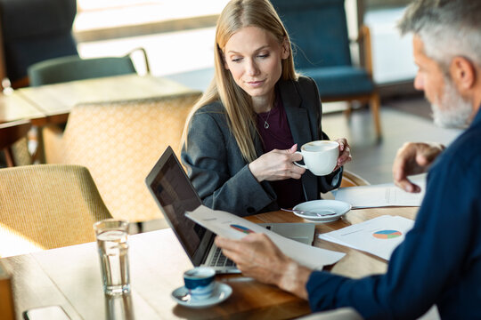 Colleagues reviewing charts over coffee in a cafe