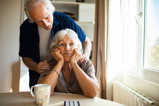 Senior man comforting worried woman at home table