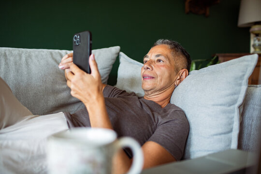 Mature man lying on sofa using smartphone