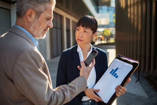 Colleagues reviewing phone and bar chart outside office