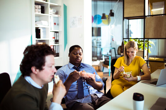 Coworkers eating lunch together at office desk
