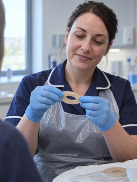 Nurse stretching an ostomy barrier ring during a medical patient consultation