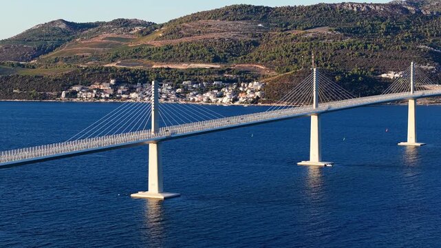 Aerial view of the Peljesac Bridge connecting the mainland to the Peljesac peninsula in Croatia, spanning the Mali Ston Bay with coastal hills in the background