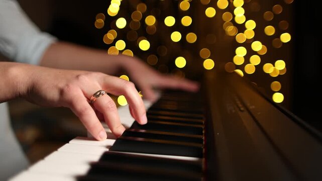 Self taught pianist plays digital piano with uneven finger placement and informal technique. Golden bokeh creates warm setting for amateur music practice.