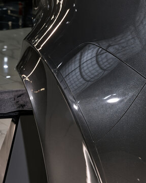 Detailed view of a dark metallic vehicle fuel door panel with subtle metallic flakes and pristine clear coat reflections.