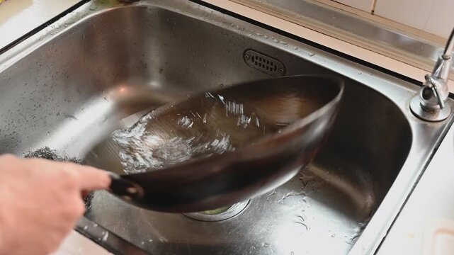 Washing a Traditional Round Iron Wok in Kitchen Sink