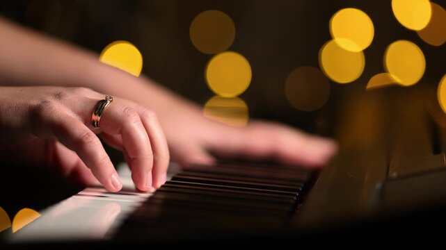 Close up shows female hands practicing piano during remote music tutoring. Golden bokeh creates warm background for online learning and musical training.