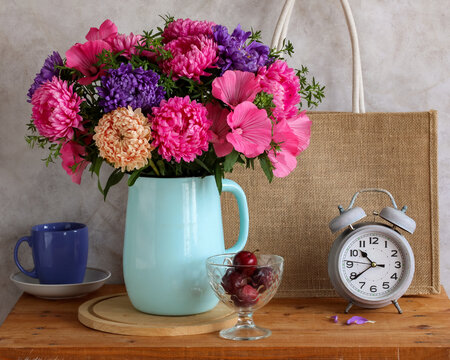 Garden flowers &mdash; asters and lavatera in a blue jug; a still life with a bouquet and plums in a rustic style.
