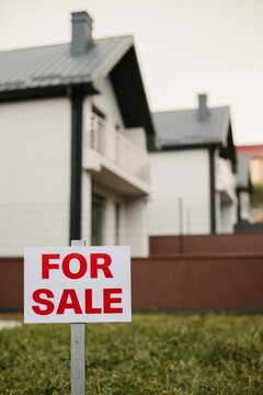 Real estate for sale sign in front of modern homes