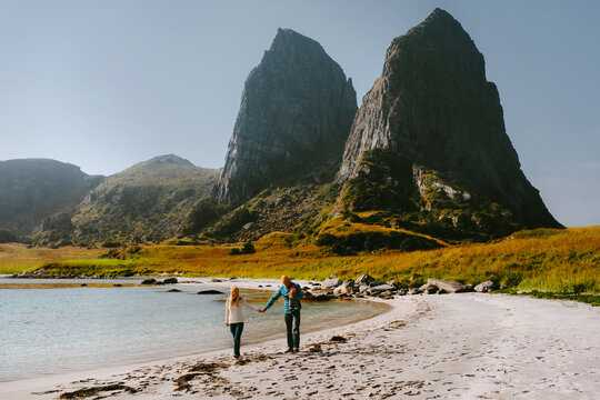 Family travel with baby in Norway parents with infant walking on sandy beach outdoor exploring Traena islands, mother father and child having fun bonding love active vacations lifestyle happy emotions