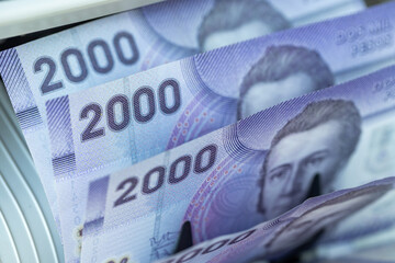 Chile money. 2000 pesos banknotes inside a currency counting machine. The most common Chilean denominations used for daily transactions. Financial concept. Close-up. © Rochu_2008