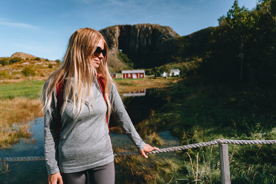 Female tourist traveling alone in Norway visiting Helgeland on summer holidays outdoor adventure active vacation and travel lifestyle, blonde woman overlooking Torghatten mountain scenic nature