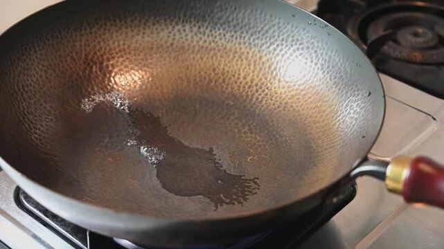 Drying a Traditional Iron Wok over a Gas Stove Flame