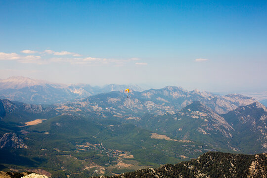 Scenic view of mountainous landscape with rolling hills and valleys under a clear blue sky, featuring a distant hot air balloon in the background